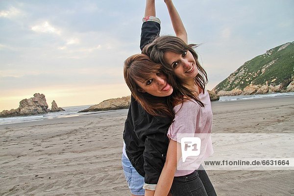 Two happy young women at El Sablón beach  Asturias  Spain