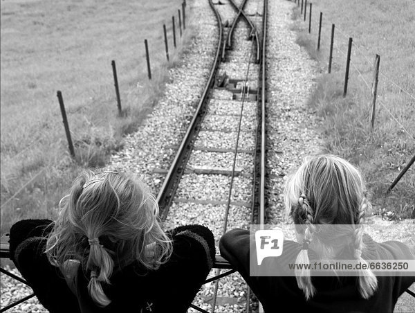 two little girls in historic wooden rail moutain train  watching for rails  funicular for Stanserhorn from town Stans  Switzerland  Swiss Alps  canton Nidwalden