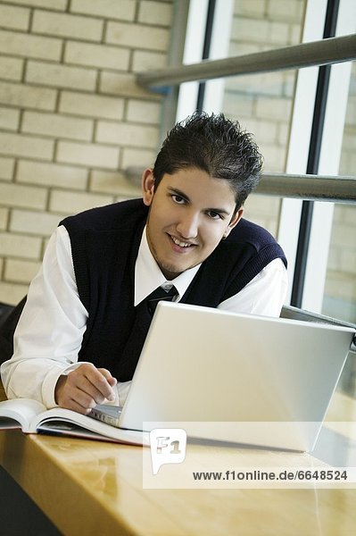 A Student In Uniform  Working On A Laptop