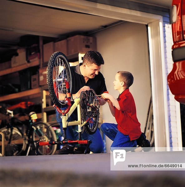 Father And Son Working On Bike Together