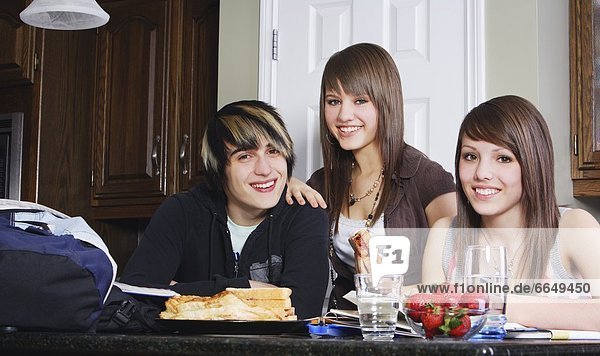 Three Friends Sitting At Dining Table  Smiling