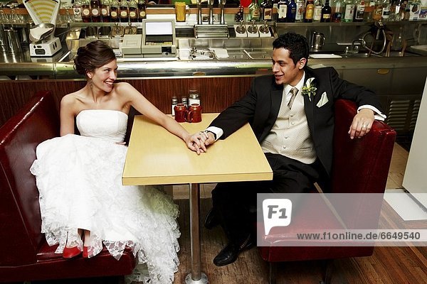 A Couple Smiling And Holding Hands In A Restaurant