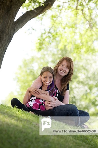 Mother And Daughter Sitting In A Park