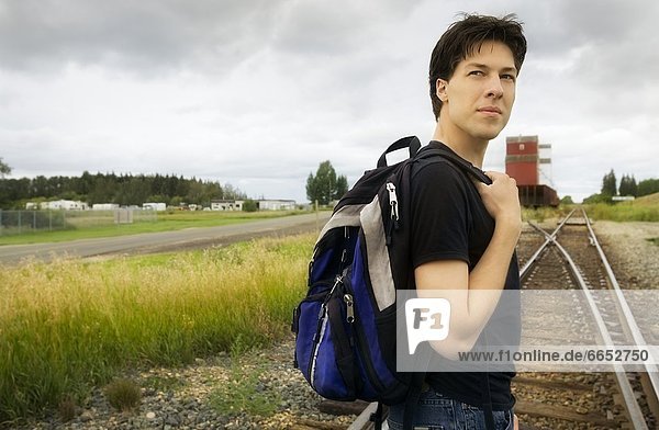 Side View Of A Man Standing On Track With Backpack