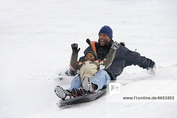 Father And Son Sledding On Snow