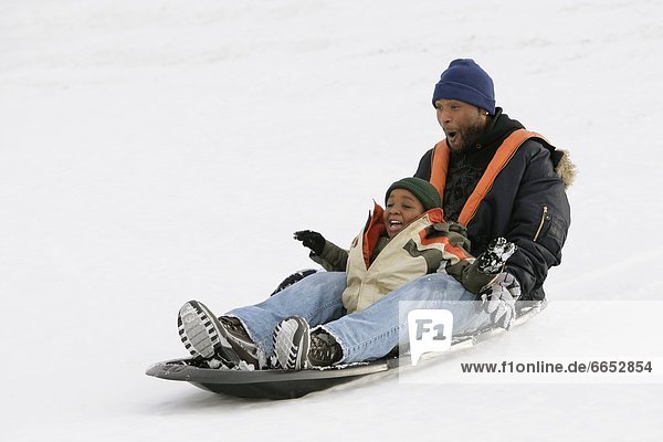 Father And Son Sledding On Snow
