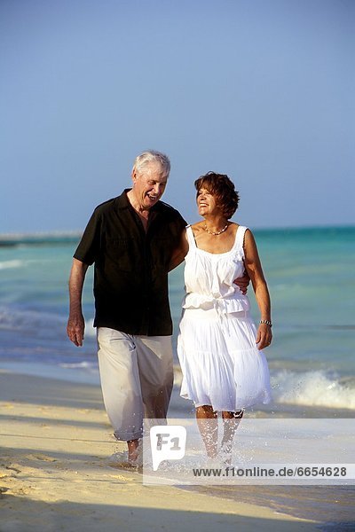 A Senior Couple Walking Along The Beach