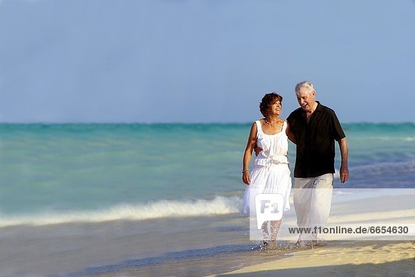 A Senior Couple Walking Along The Beach