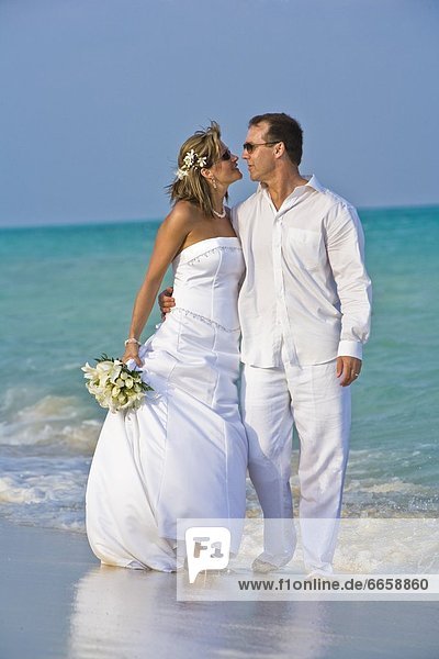 Braut und Bräutigam umarmen am Strand