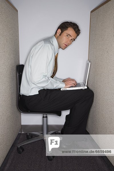 Man On Laptop In Tiny Cubicle