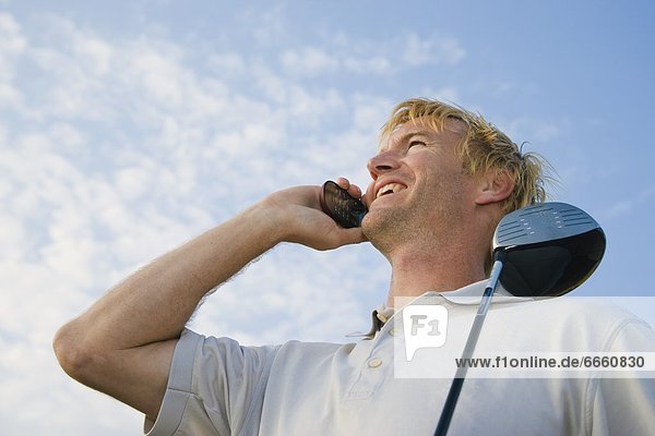 Man Holding Golf Club  Speaking On Cell Phone