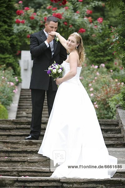 Bride And Groom On Stone Stairs In Rose Garden