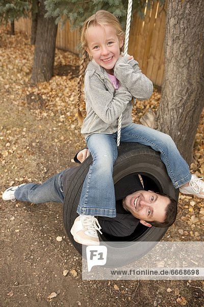 Father And Daughter On Tire Swing