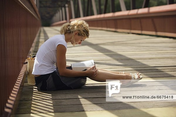 Woman Sitting On A Boardwalk And Reading