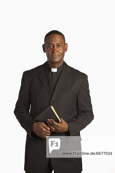 A Man Wearing A White Clerical Collar Holding A Bible