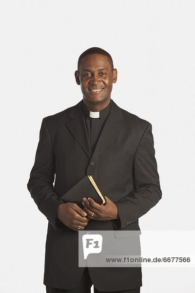 A Man Wearing A Clerical Collar And Holding A Bible
