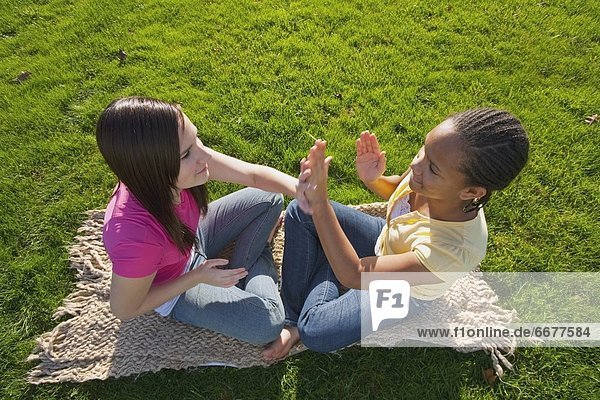 Two Girls Clapping Hands Together In A Game In The Park