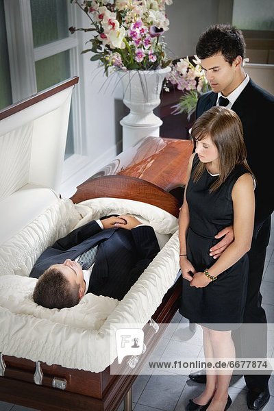 A Man And A Woman Viewing A Body In A Coffin