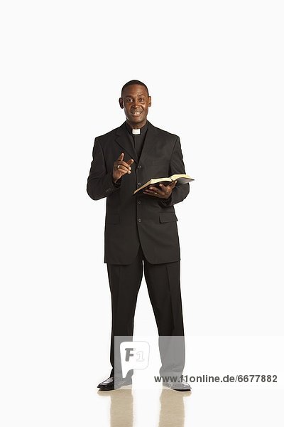 A Man Wearing A Clerical Collar And Preaching From The Bible