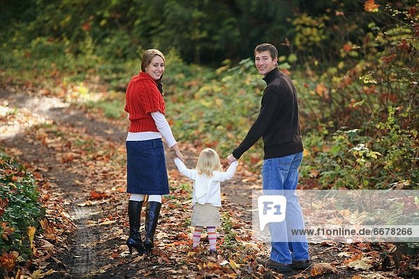 A Family Walking Down A Path In Autumn