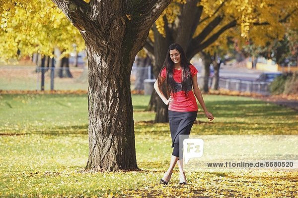 A Teenage Girl Walking Through A Park In Autumn