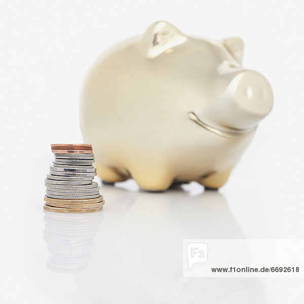 A Stack Of Coins Beside A Piggy Bank
