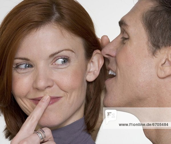 Man whispering secret in woman's ear