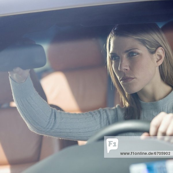 Woman in car adjusting rearview mirror