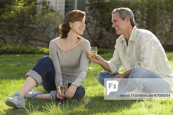 Couple sitting in grass drinking wine