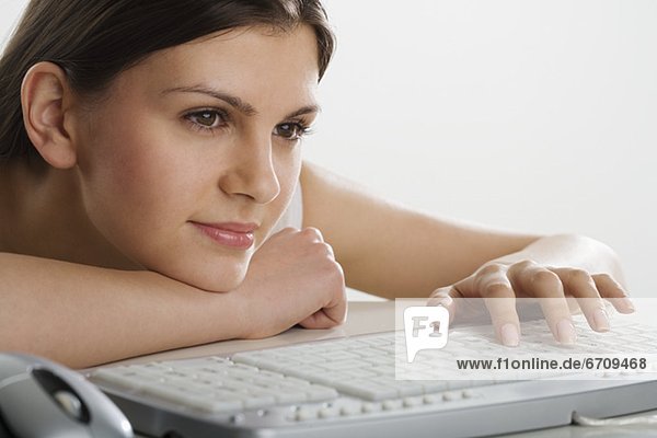 Woman leaning on table using computer keyboard