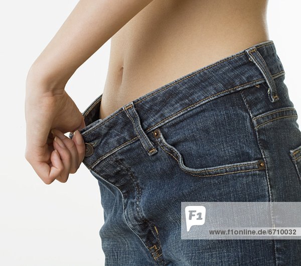Close up of woman holding waist of pants away from stomach