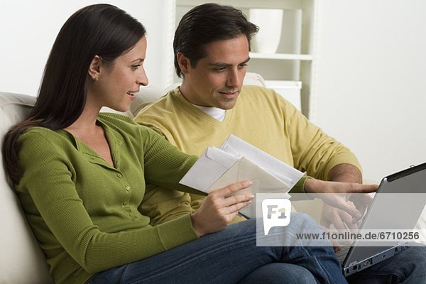 Couple with bills and laptop on sofa
