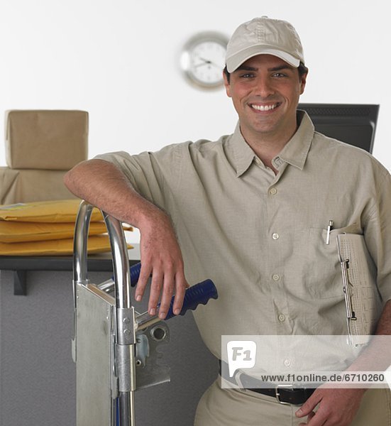 Deliveryman smiling and leaning on hand truck