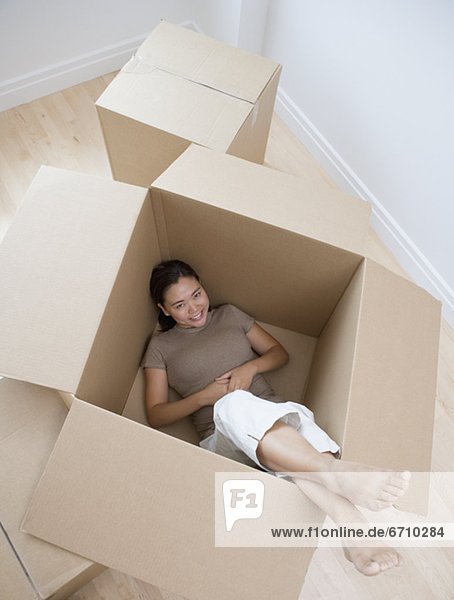 Woman sitting in empty moving box