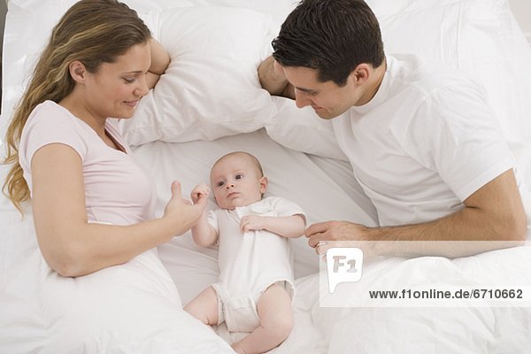 Parents smiling at baby in bed