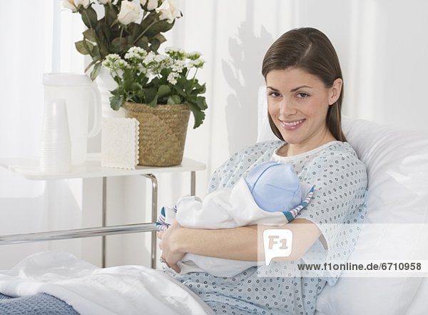 Portrait of mother holding newborn baby in hospital