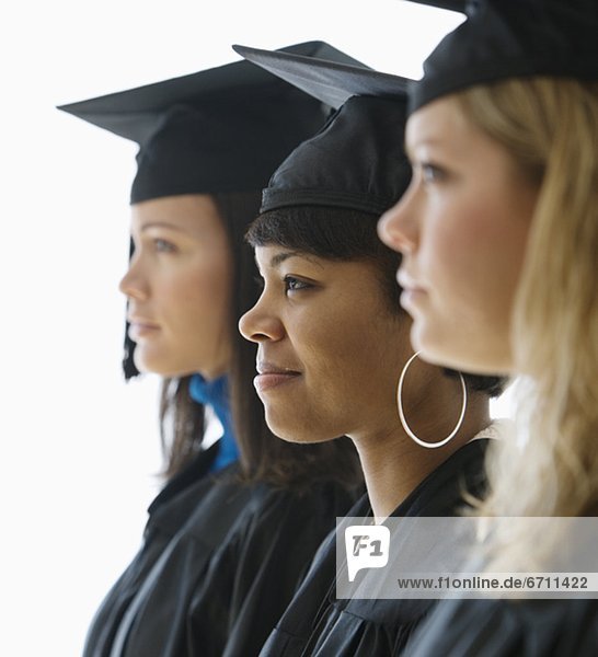 Multi-ethnic women wearing graduation cap and gown