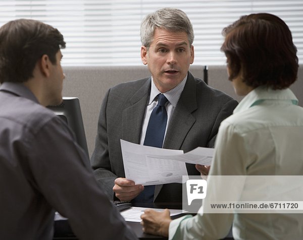 Businessman talking to couple in office