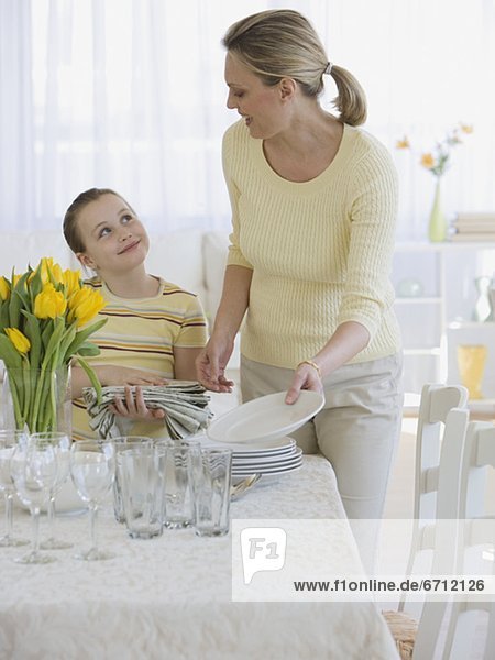 Mother and daughter setting table