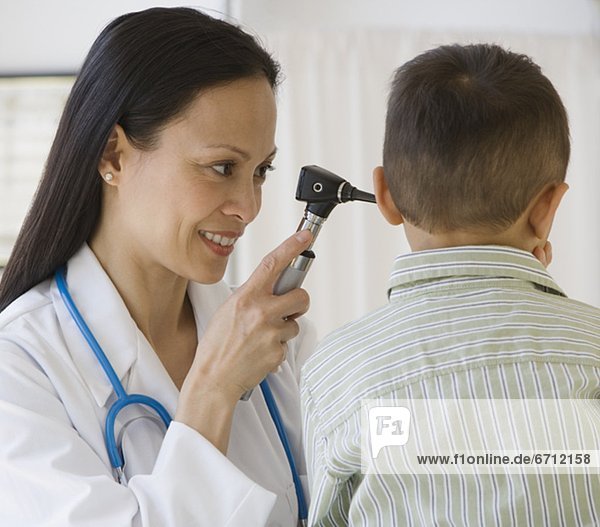 Asian female doctor examining boyÕs ear