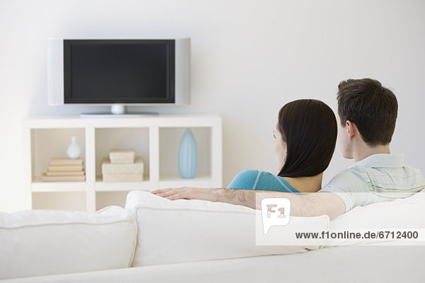 Couple watching television on sofa