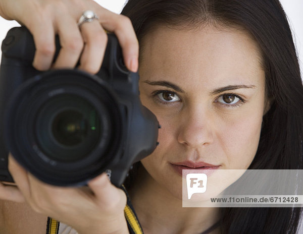 Woman holding camera next to face