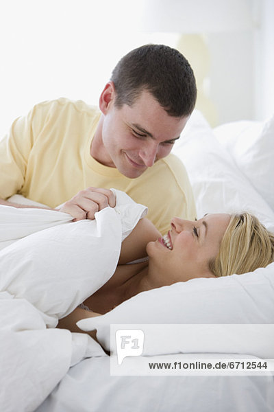 Couple smiling at each other in bed