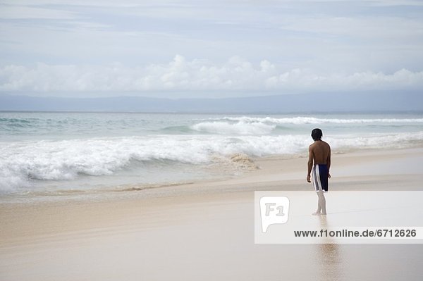 Teenager Looking At Surf On Beach