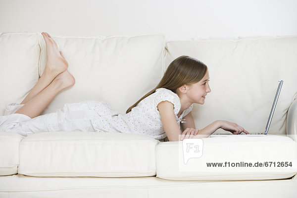 Girl using laptop on sofa