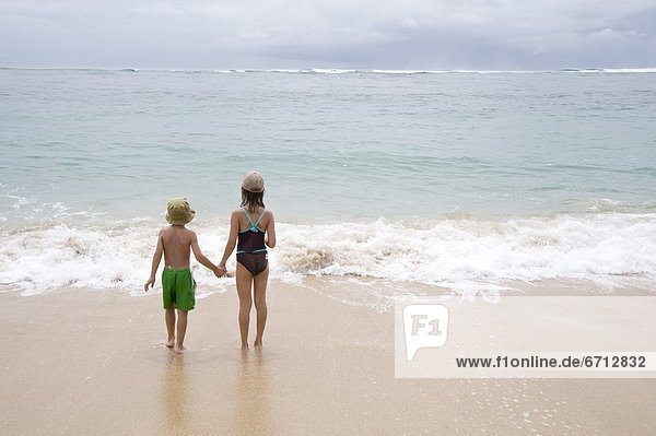 Children On Sandy Beach Looking At Sea