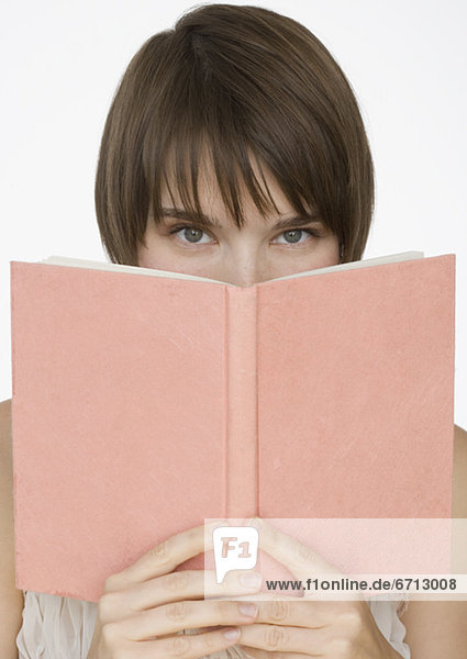 Woman holding open book over face