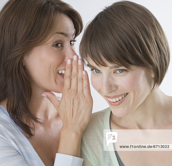 Woman telling secret to friend