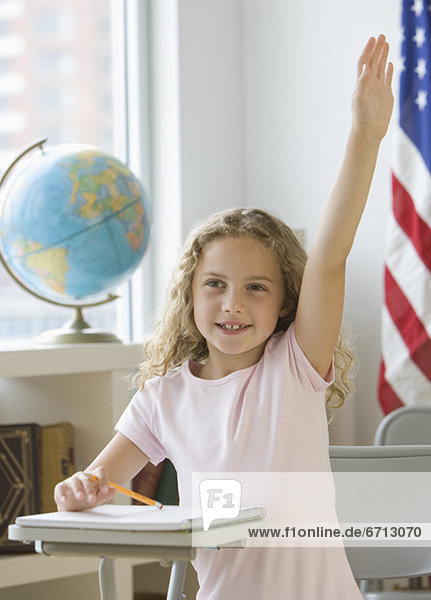 Girl raising hand at school desk