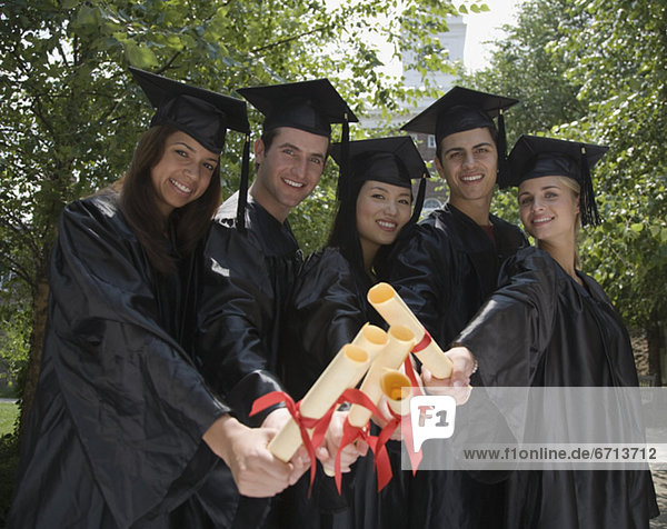 Group of college graduates holding diplomas